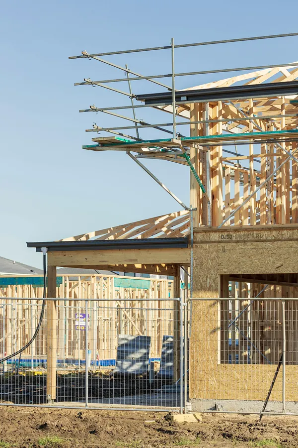 A new timber-framed house going up behind scaffolding.
